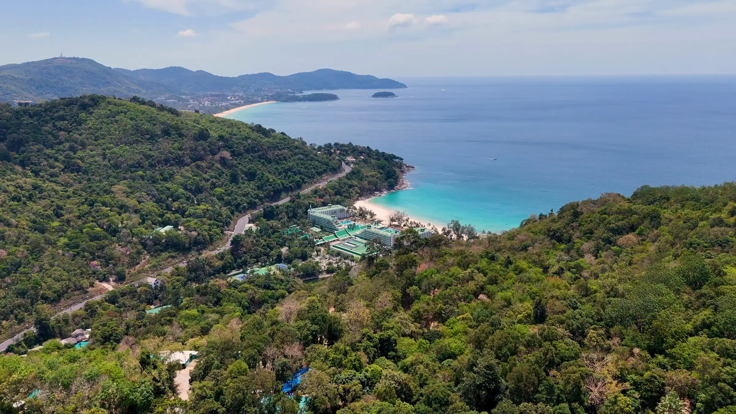 Forested headlands above a turquoise bay on the coast of Phuket, seen from the air