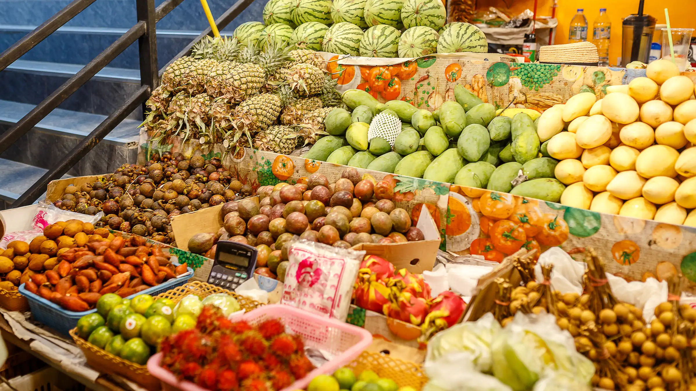 A Thai market stall piled with pineapples, watermelons, mangoes and other tropical fruit
