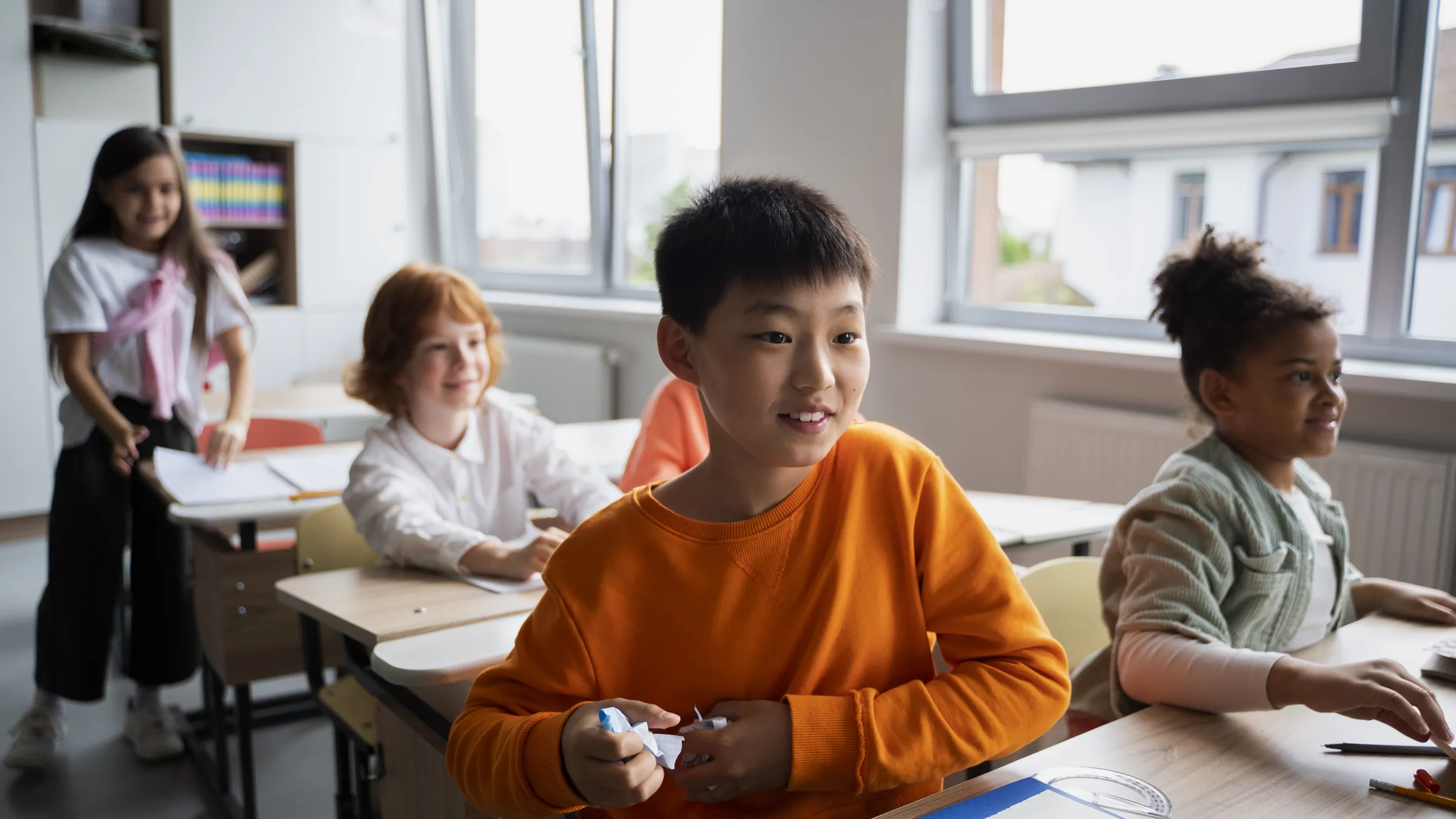 Children of different backgrounds working at their desks in a bright classroom