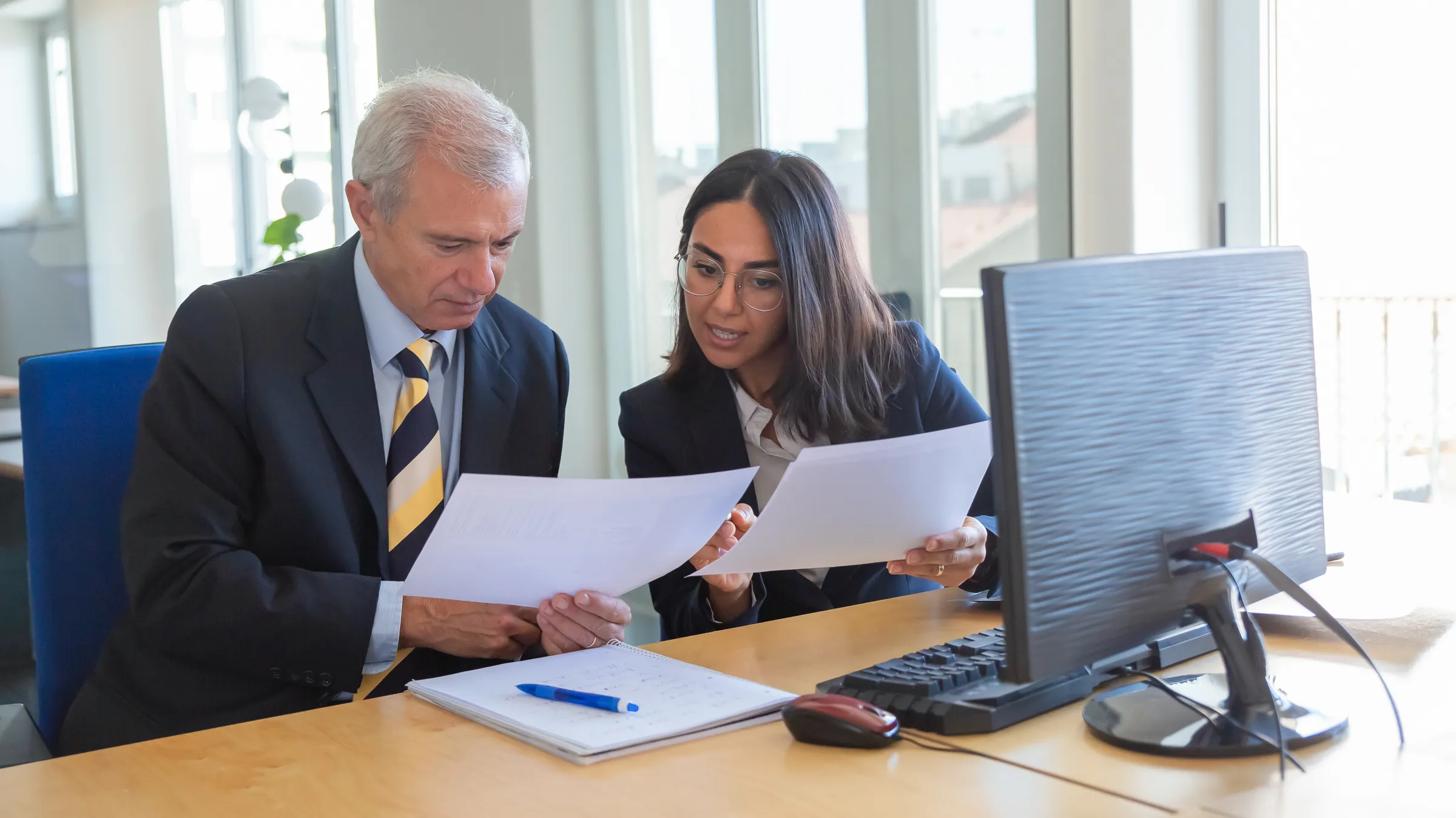 Legal adviser explaining the details of a document to a client at an office desk