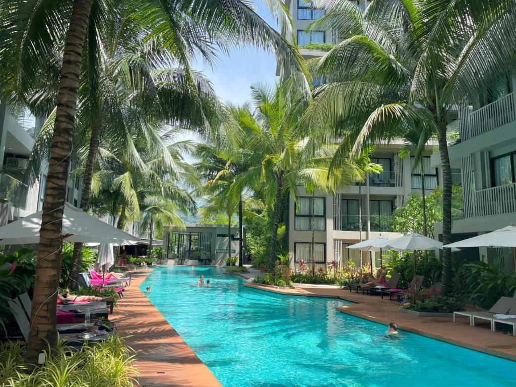 Luxury resort in Phuket featuring a long outdoor pool lined with palm trees and sun loungers